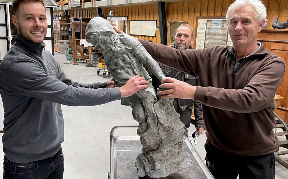 Zum Bild: Metallbauer und Restaurator Felix König (links) übernimmt vom Heimatvereinsvorsitzenden Klaus Daum (rechts) die Brunnenfigur, um sie in seiner Werkstatt in Lüdenscheid genauer unter die Lupe zu nehmen. Im Hintergrund der Finanzexperte und Beirat im Verein, Klaus Sonneborn. (Foto: Heimatverein Landwirtschaft und Brauchtum Bad Berleburg)